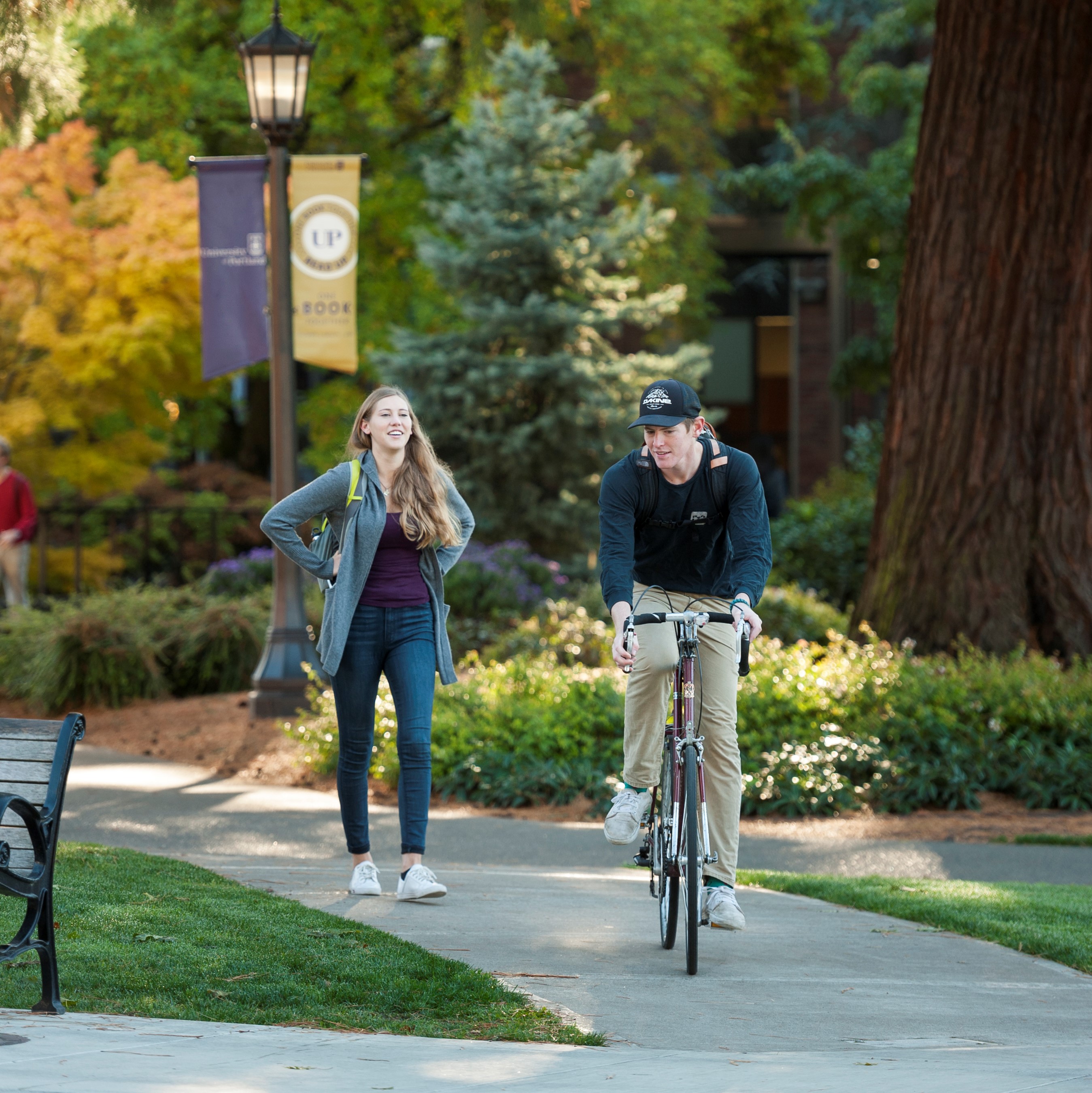 students walking next to other student on a bike on campus