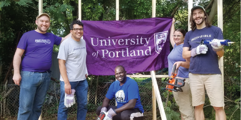 Alumni holding different tools for tiny house building.