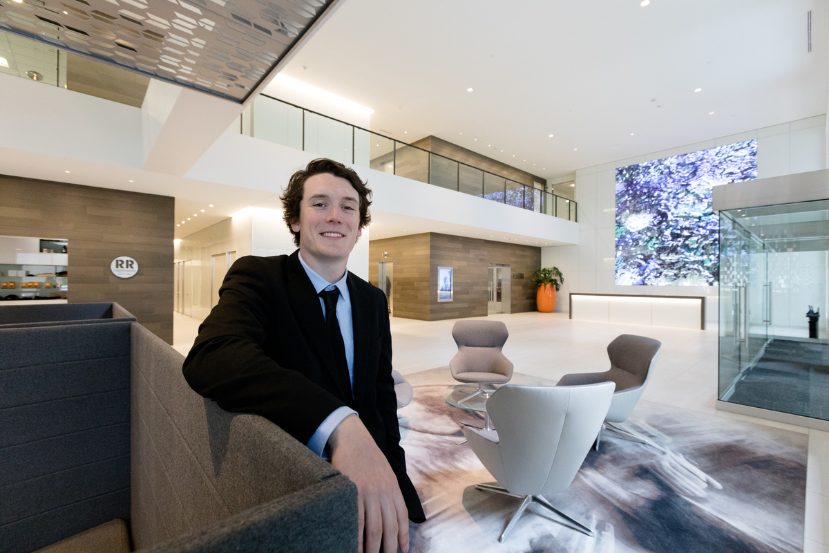 A well-dressed man in a suit and tie stands in a stylish lobby, showcasing a professional appearance amidst luxurious surroundings.