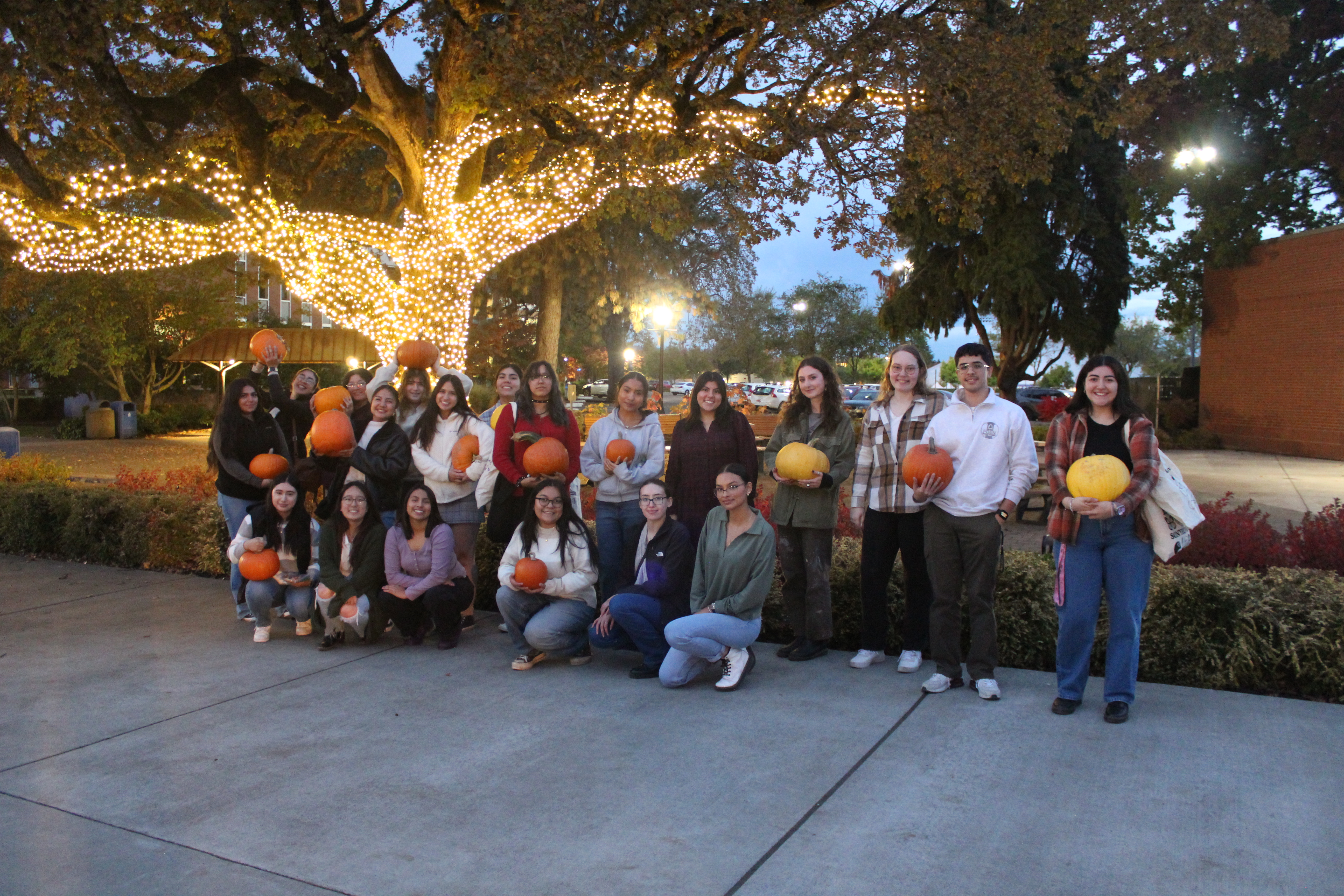Students standing holding pumpkins, smiling