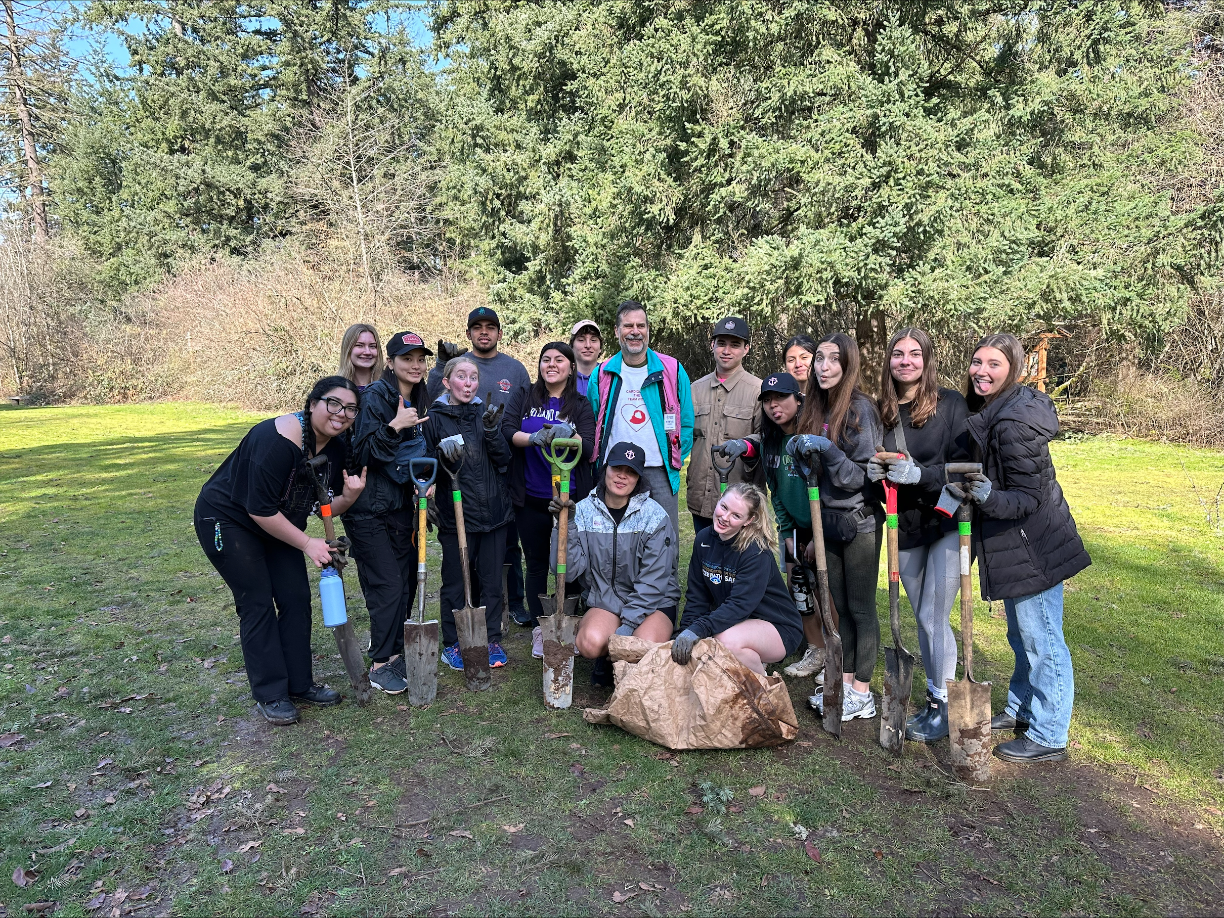 a service and justice coordinator event with field halls.  students standing outside with shovels after planting trees.