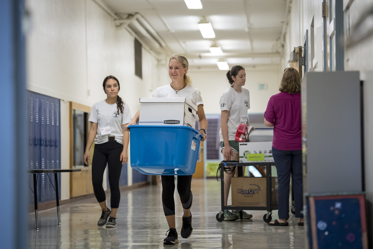 Students volunteering carrying a box in an elementary school