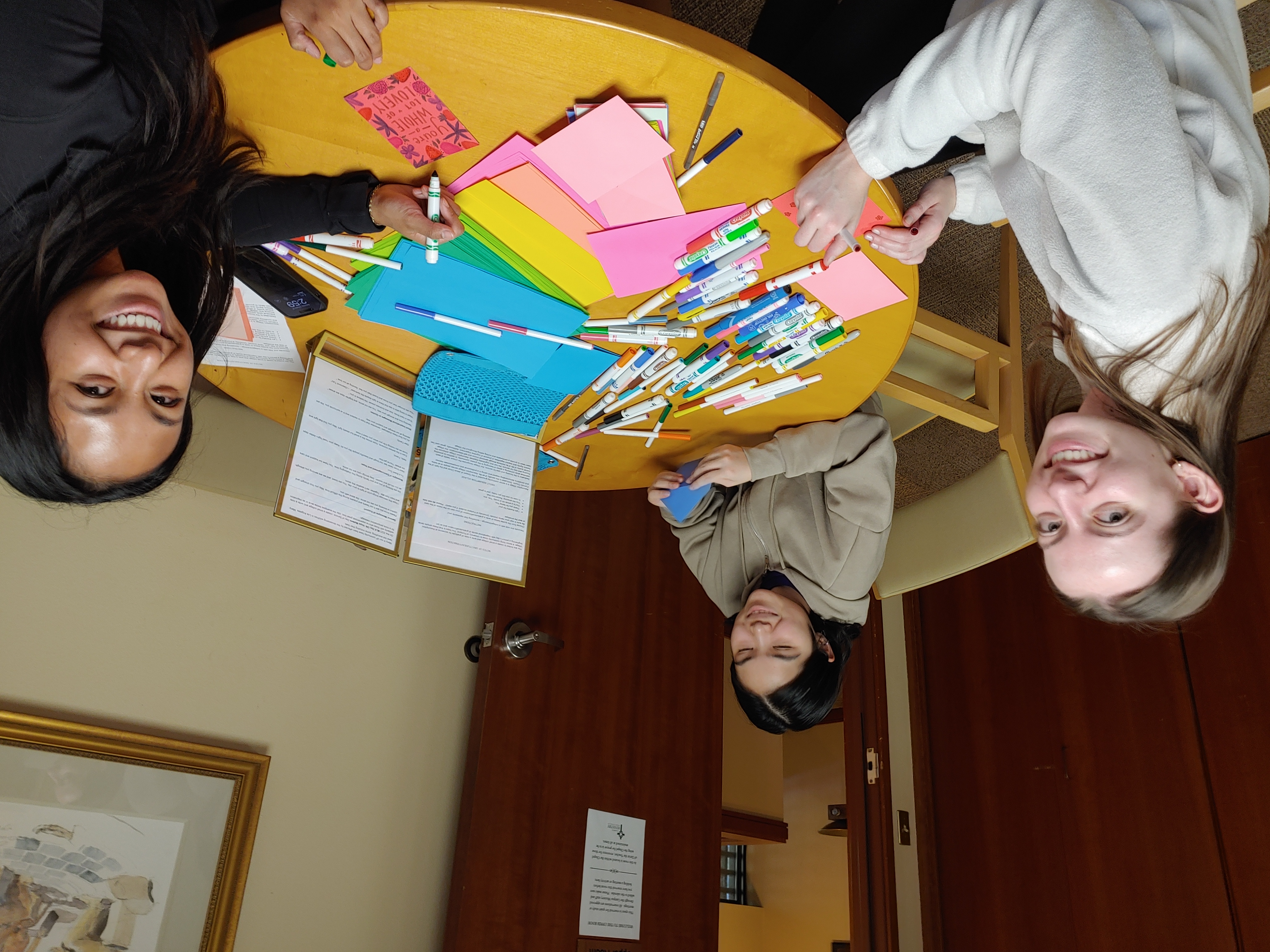 Three students around a table making kindness cards