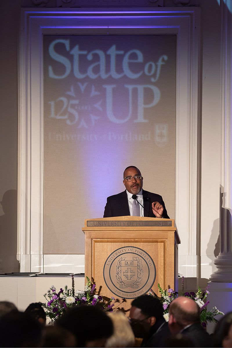 President Kelly standing at podium giving his State of UP address.