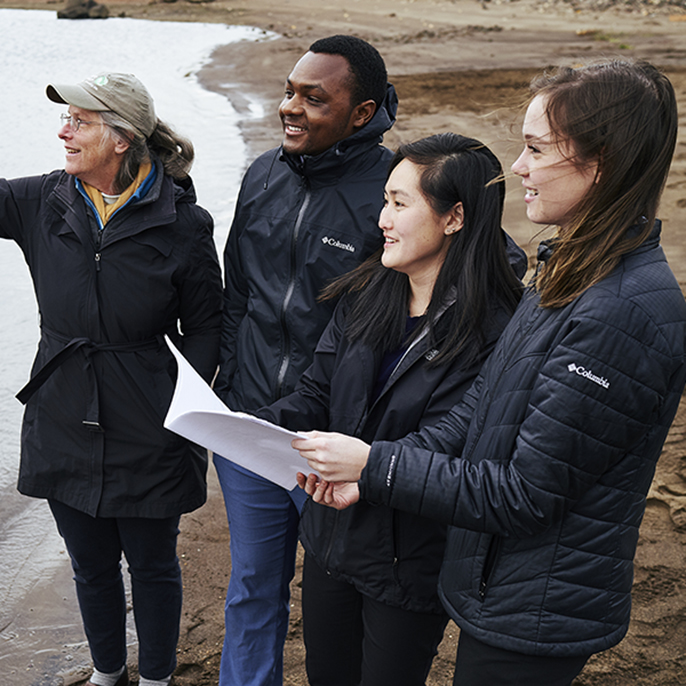 students work with professor near water