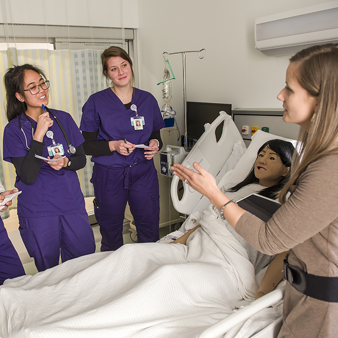 students and professor stand around Simulated Health Center
