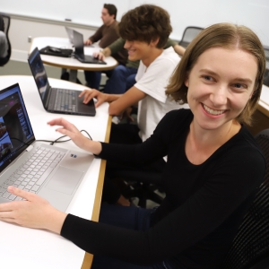 A student sits in front of a laptop computer.