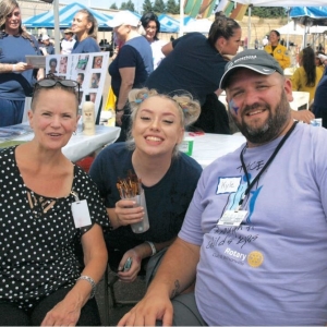 Kyle Bunch sits at an outdoor table under tents with several people gathered for a party.