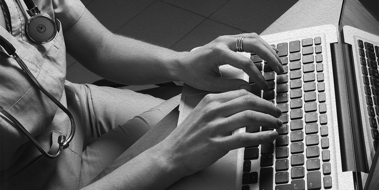 woman in scrubs typing on a keyboard
