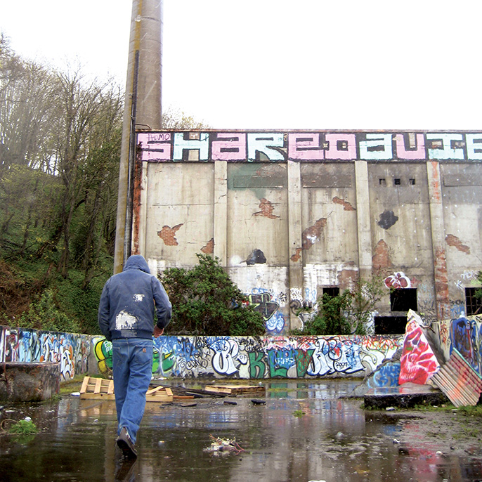 Man walking in front of building with graffiti 