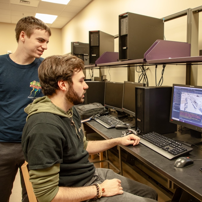 Two students work at a computer in a lab