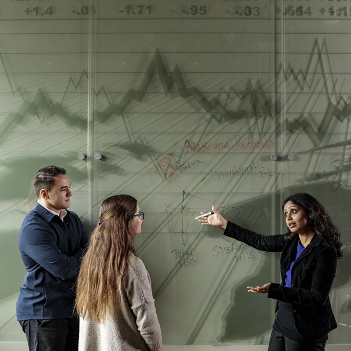 professor teaching two students in front of board