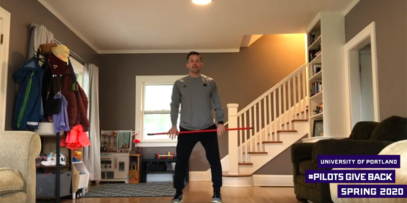 Michael Rittman standing in living room with "University of Portland Pilots Give Back Spring 2020" logo