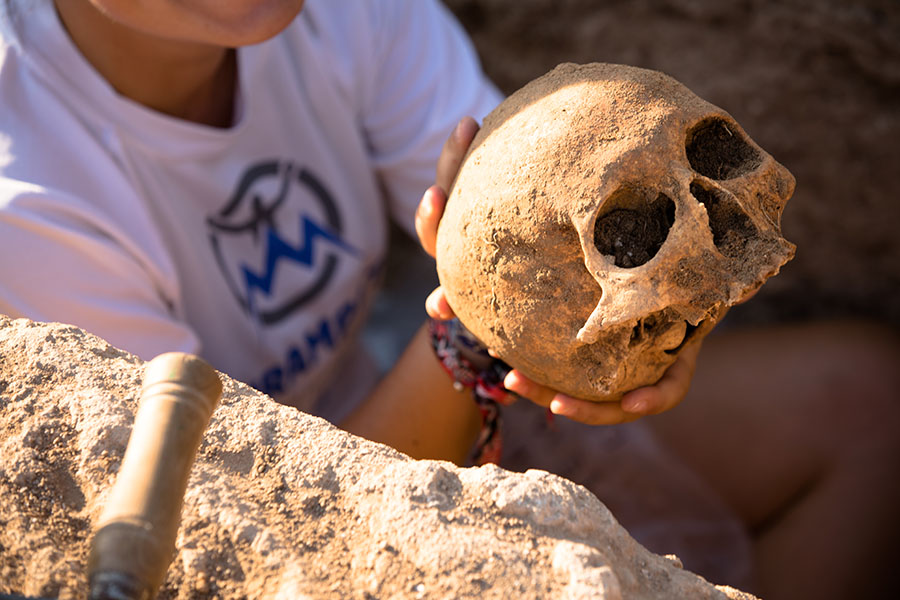 Hands cradling a skull at archeological dig site