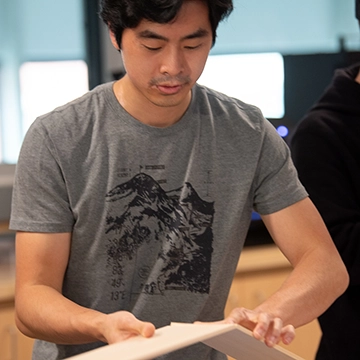 A student examines the joint of two wooden boards in the maker lab
