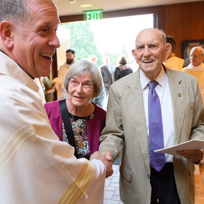 Al shaking hands with father ed obermiller at the university chapel