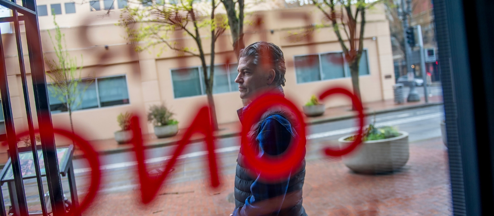 Andy standing on the sidewalk photographed through the window glass of the central city concern office