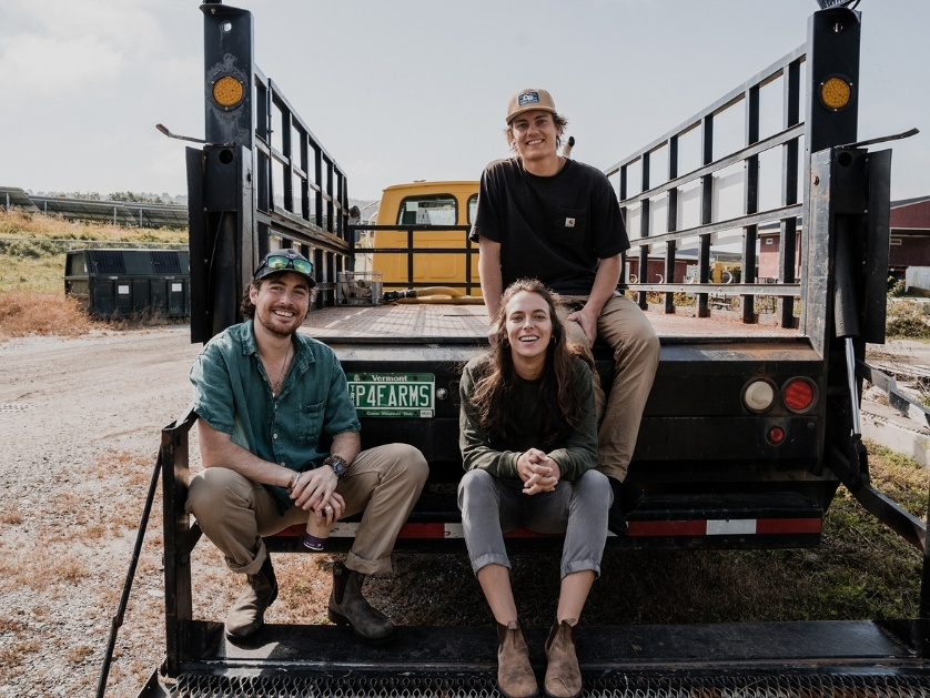 three people sitting on the back of a truck