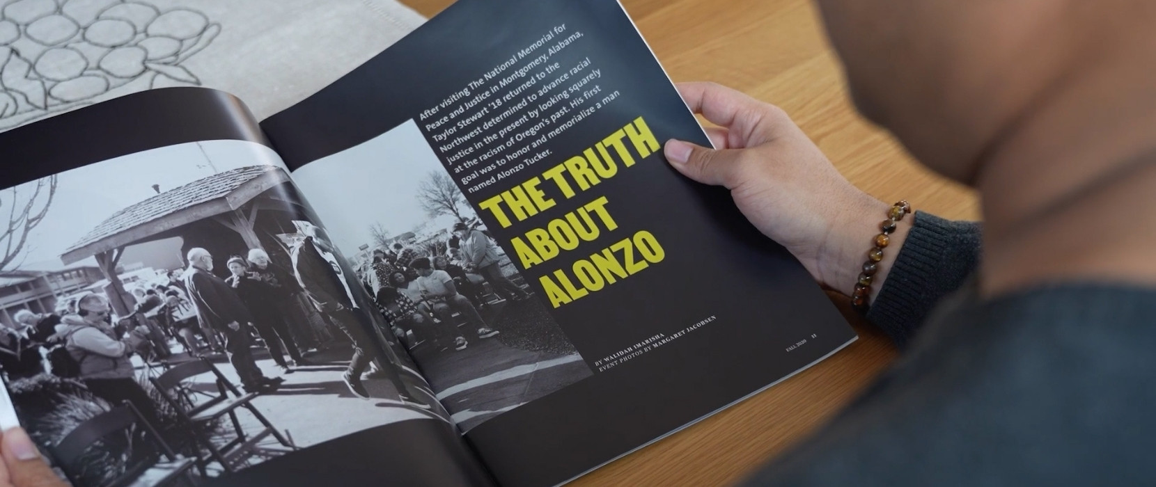 A person is reading an issue of Portland magazine that is open on a table