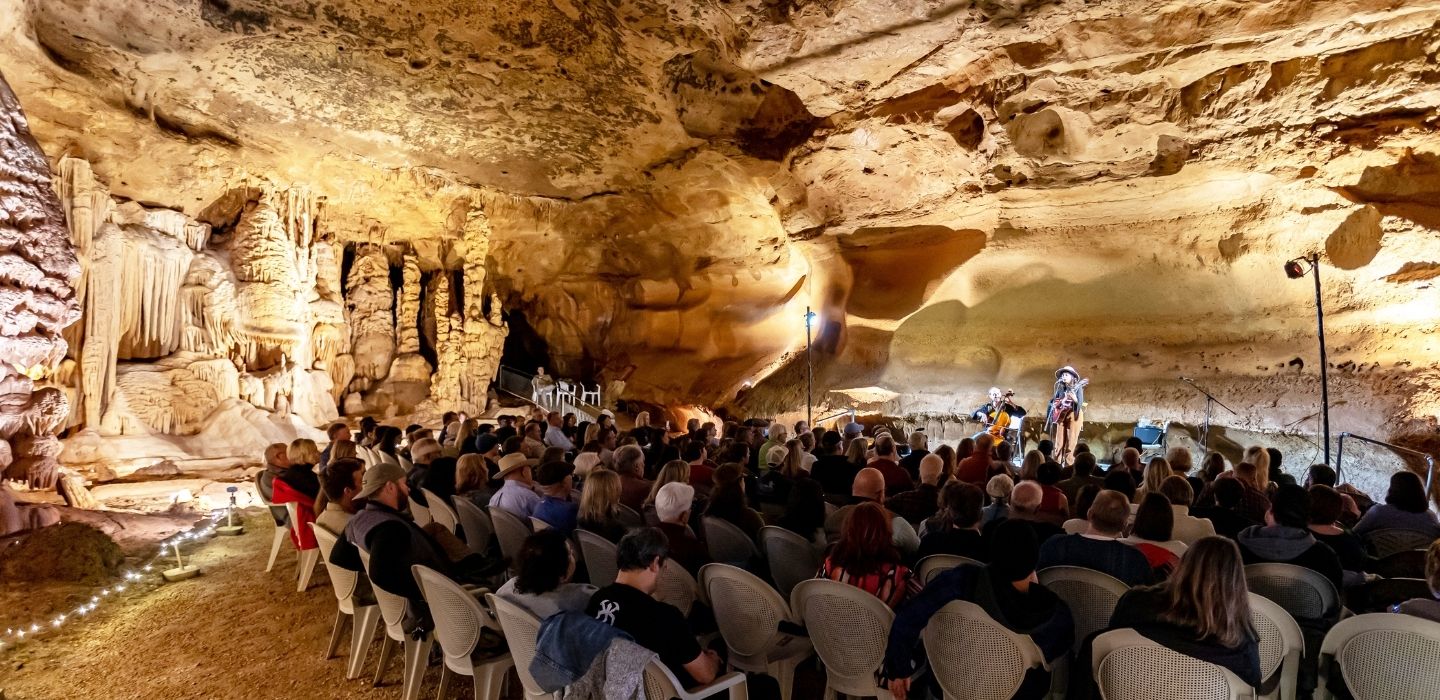 A audience of people watching a musical performance in an underground cavern