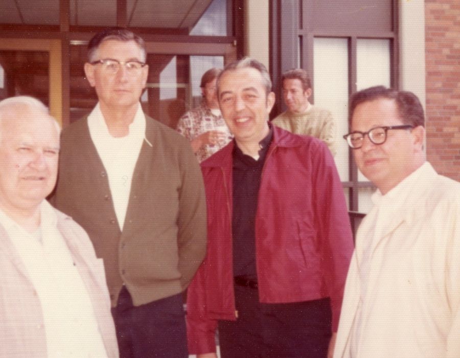 Three men standing outside a building in a 1970's era photograph