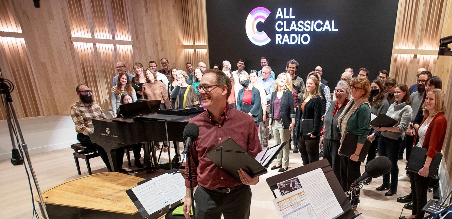 David De Lyser stands in the recording studio of OPB with the Choral Arts Ensemble ready to perform on live radio
