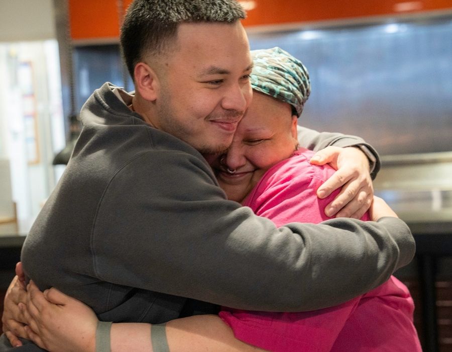 Mo, aka Monique Quintana, hugs student Ray Castro in the kitchen of Bauccio Commons.