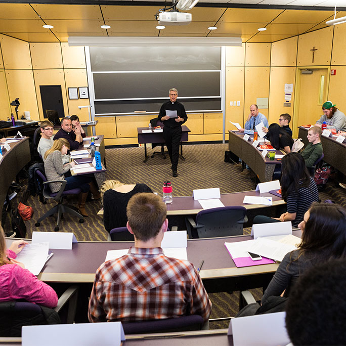 Father Mark Poorman stands in front of a class of students teaching in Franz Hall