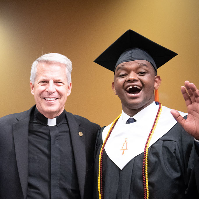 Father Mark Poorman poses at a graduation with a student