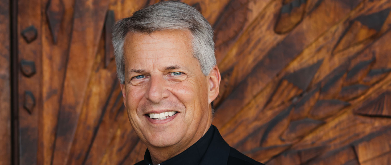 Father Mark Poorman poses in front of the Chapel of Christ the Teacher
