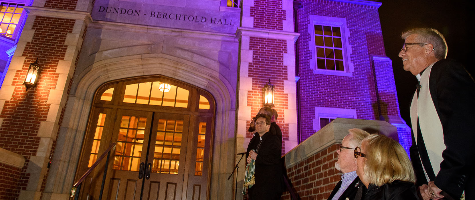 Father Mark Poorman stands outside Dundon-Berchtold hall at the dedication