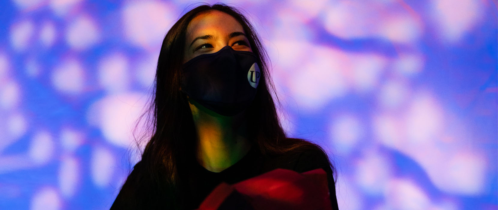 Kat Yo wears a mask on stage, holding the dragon puppet