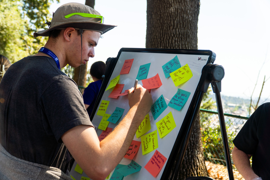 Photo of person with a wide-brim hat writing on a sticky note at the Wellness Fair.